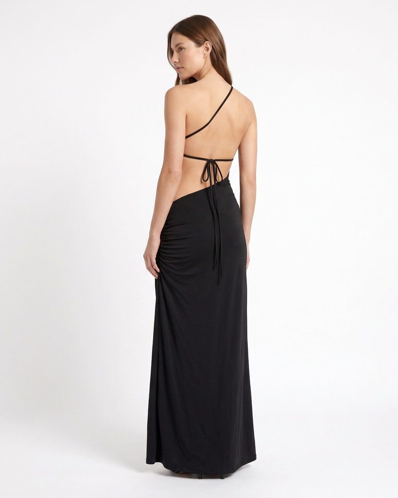 Vestido largo AVRA negro en modelo, vista de espalda en tres cuartos con espalda descubierta, tira diagonal y amarre fino.