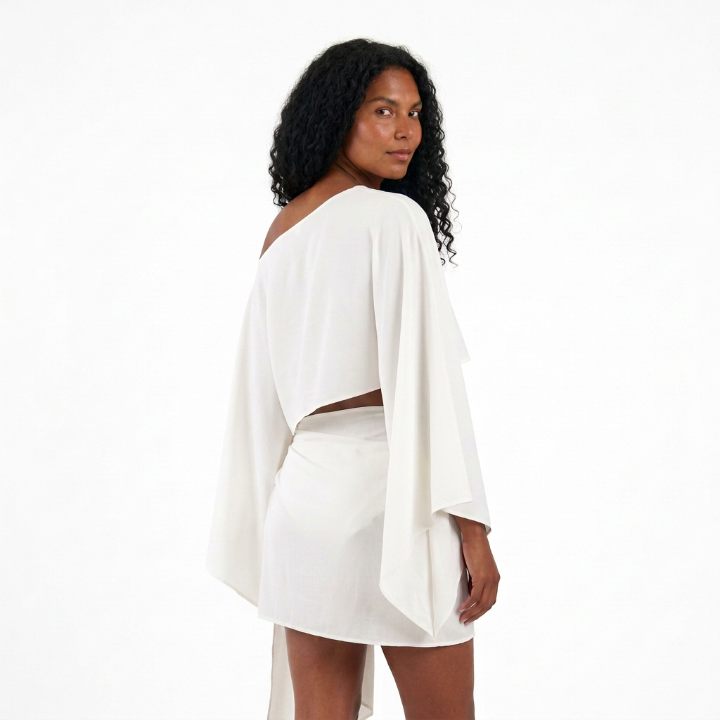 Conjunto ZAMNA blanco de MIZZBOGI sobre modelo, vista trasera tres cuartos del top asimétrico y pareo corto.